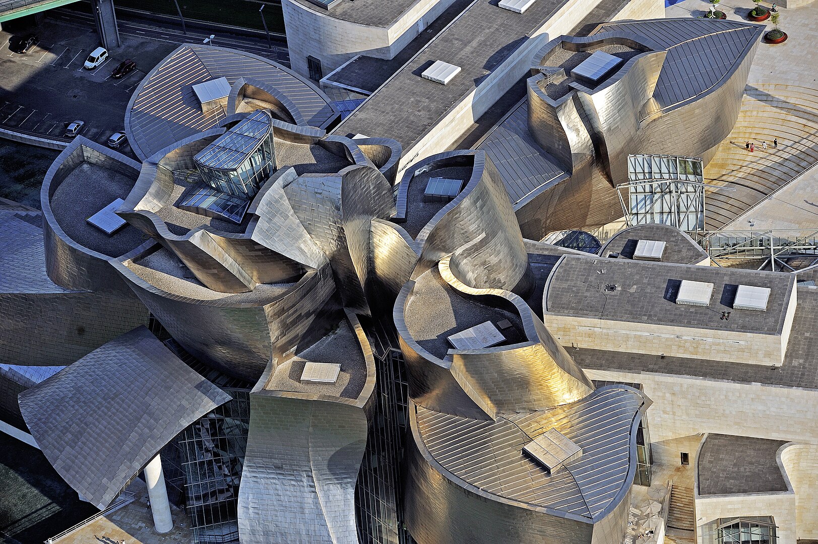 Aerial view of a complex, metallic architectural structure with curved, interlocking forms and reflective surfaces, surrounded by a parking area. Try drafting this using traditional straightedges and pencils. Aerial view of the Bilbao Guggenheim museum by Mikel Arrazola - EJ-Irekia via [Wikimedia](https://commons.wikimedia.org/w/index.php?curid=55338997)